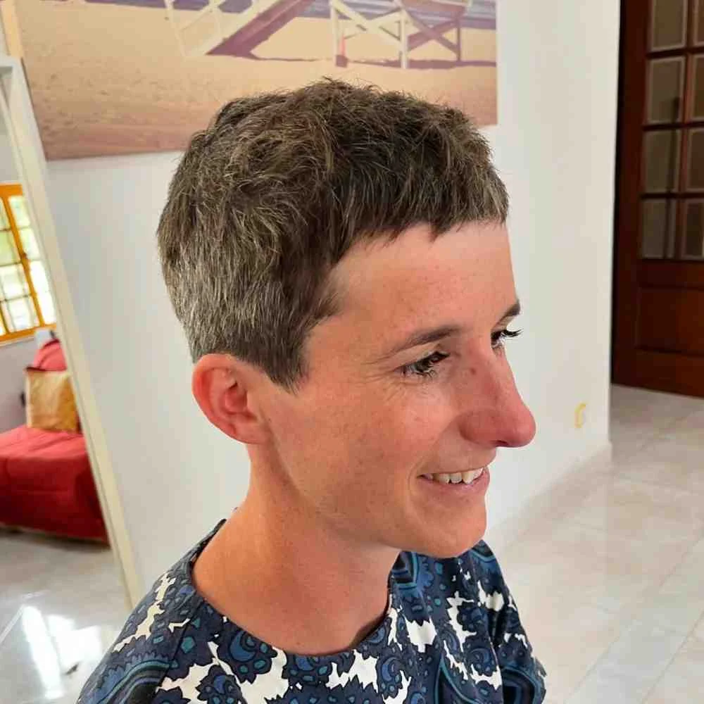 Woman over 40 with soft platinum feathered pixie cut smiling in natural light.