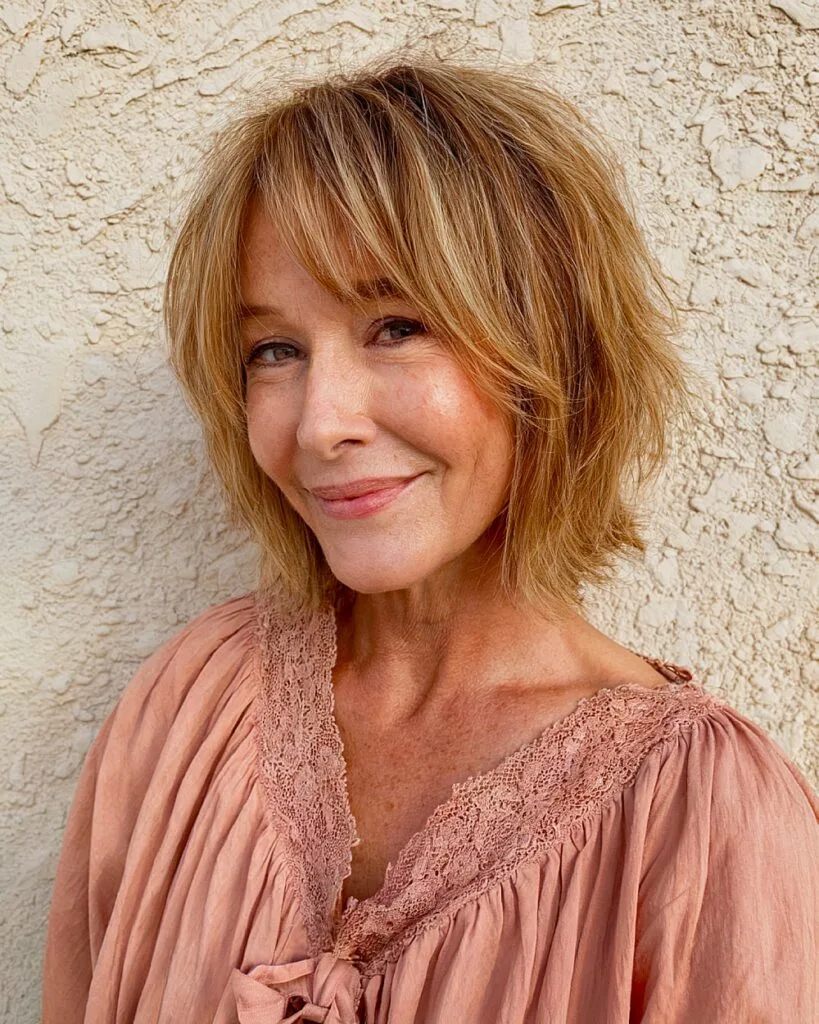 Shaggy choppy bob with feathered ends on older woman with honey-blonde layers and light texture