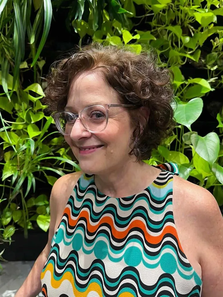 Short auburn curly bob with retro glasses and freckles