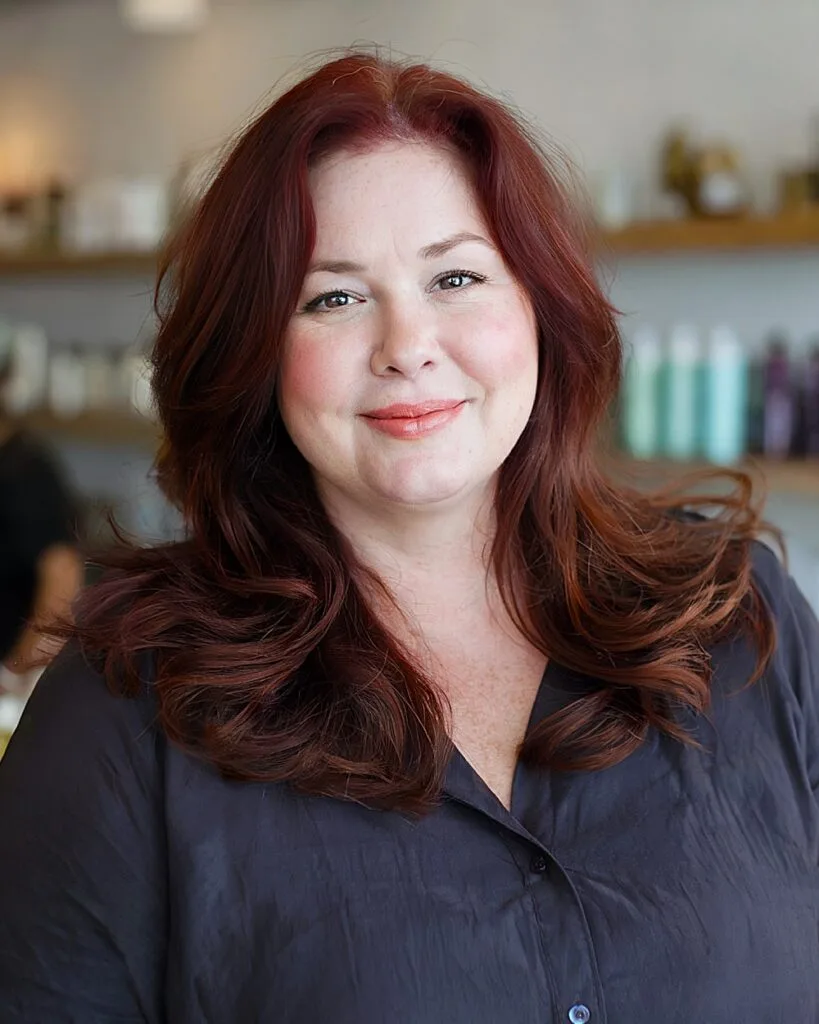 Flattering medium haircut for round faces with rich auburn color and soft layering