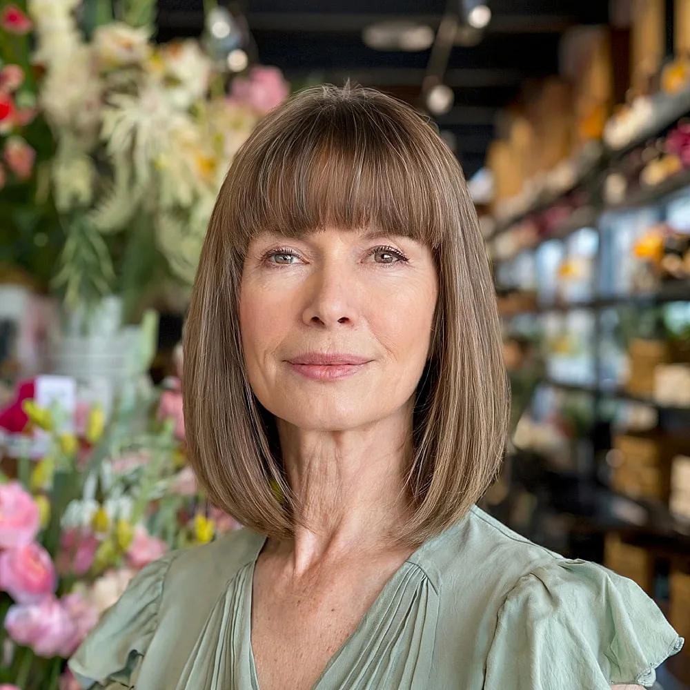 Straight long bob with full bangs and light brown color for women over 50