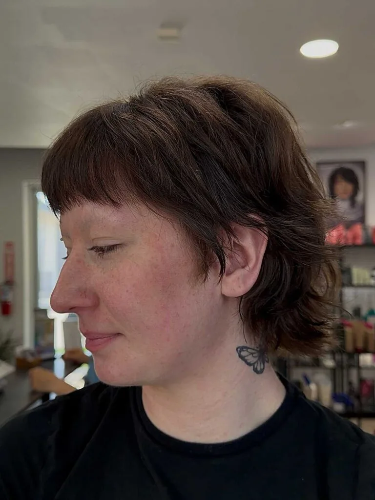 Warm brown bixie mullet with choppy bangs and layers