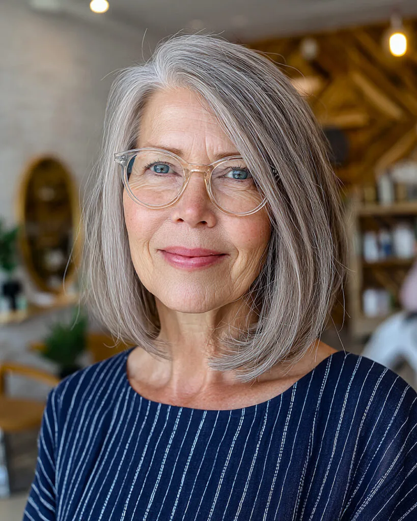 Blunt shoulder-length bob for women over 50 with sleek gray tones and deep side part