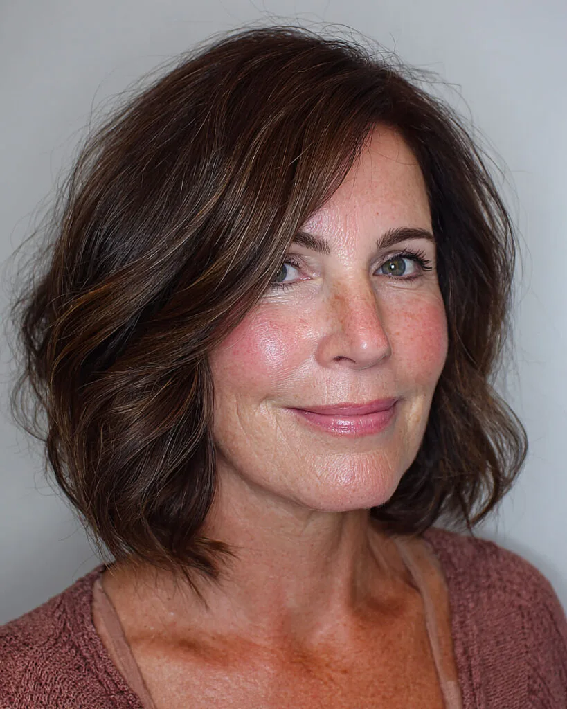 Chin-length inward flip bob for women over 50 with rich brunette tones and side part