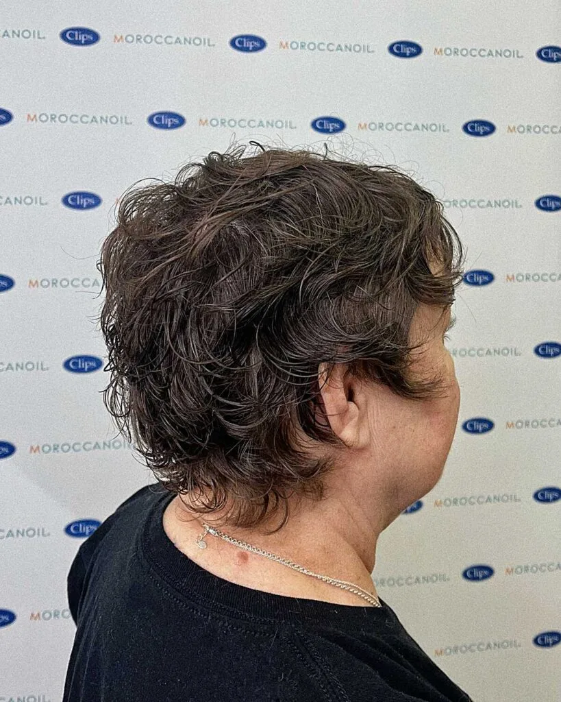 Curly dark bixie with tapered nape, seen from behind