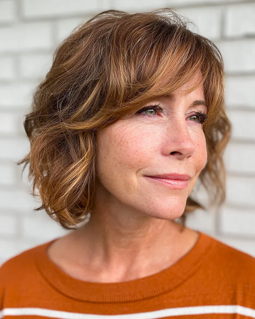 Light choppy long bob for women over 50 with side bangs and soft golden brown color