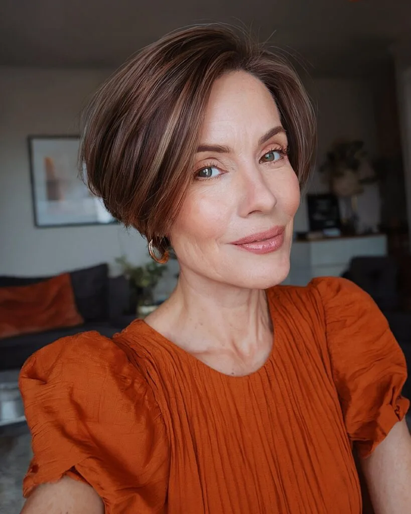 Side-parted sleek pixie bob for older women with smooth brunette hair and soft volume