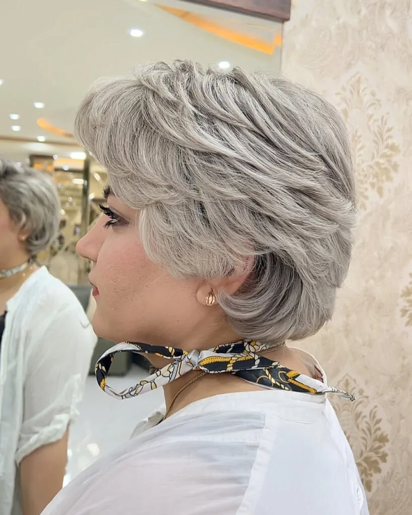 Silver feathered pixie cut for older women with thick hair and soft layers adding volume and movement
