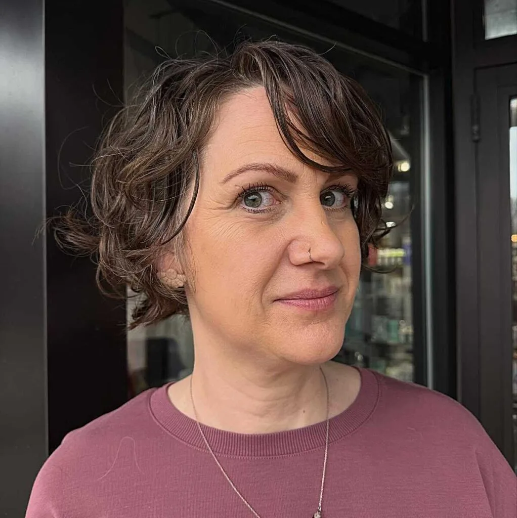 Tousled wavy brunette bixie with side-swept curly bangs