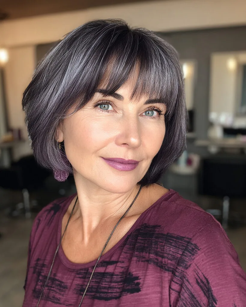 Modern chin-length bob with arched bangs and subtle face-framing layers for mature women