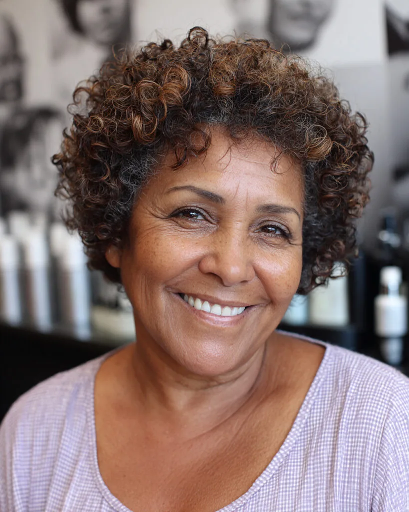 Short voluminous curls with subtle highlights for women over 50 with natural texture