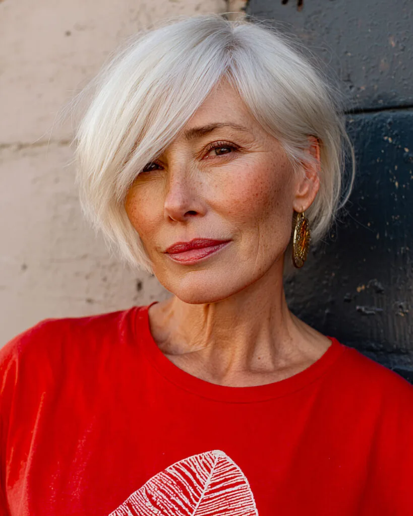 Sleek white pixie bob featuring long side bangs for older women