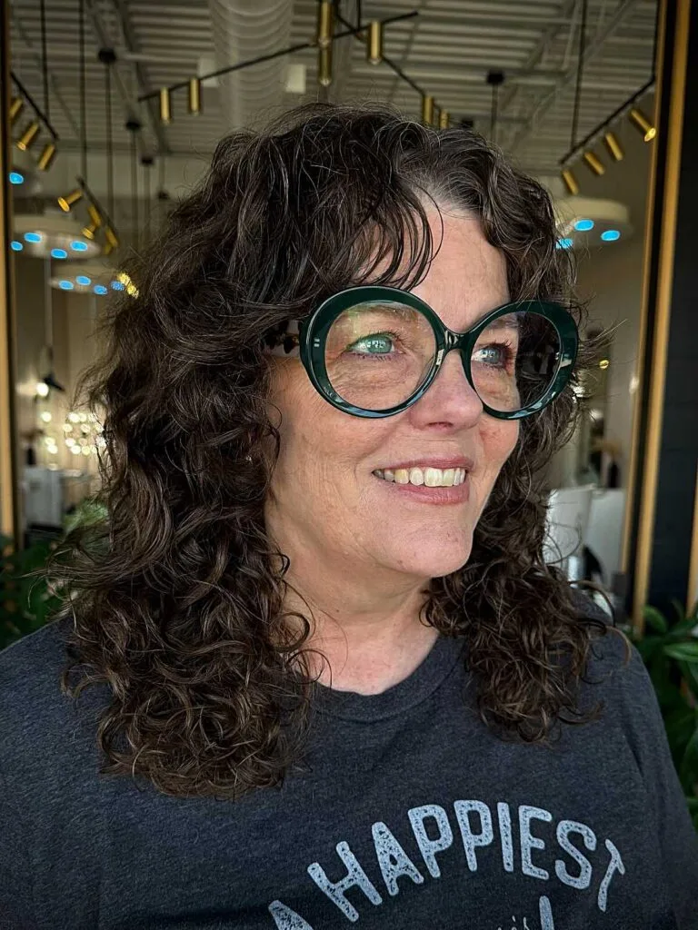 Dark curly shoulder-length shag with round glasses