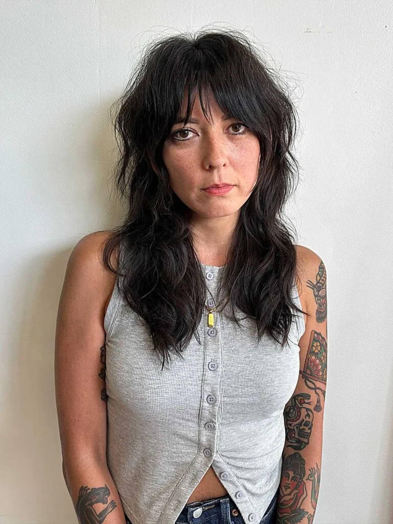 Dark wavy shag haircut with choppy bangs and layers