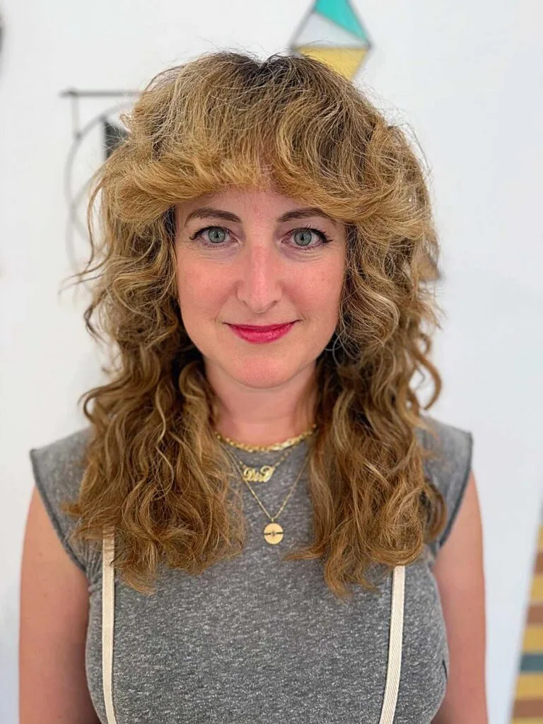 Golden blonde curly shag with bangs and volume