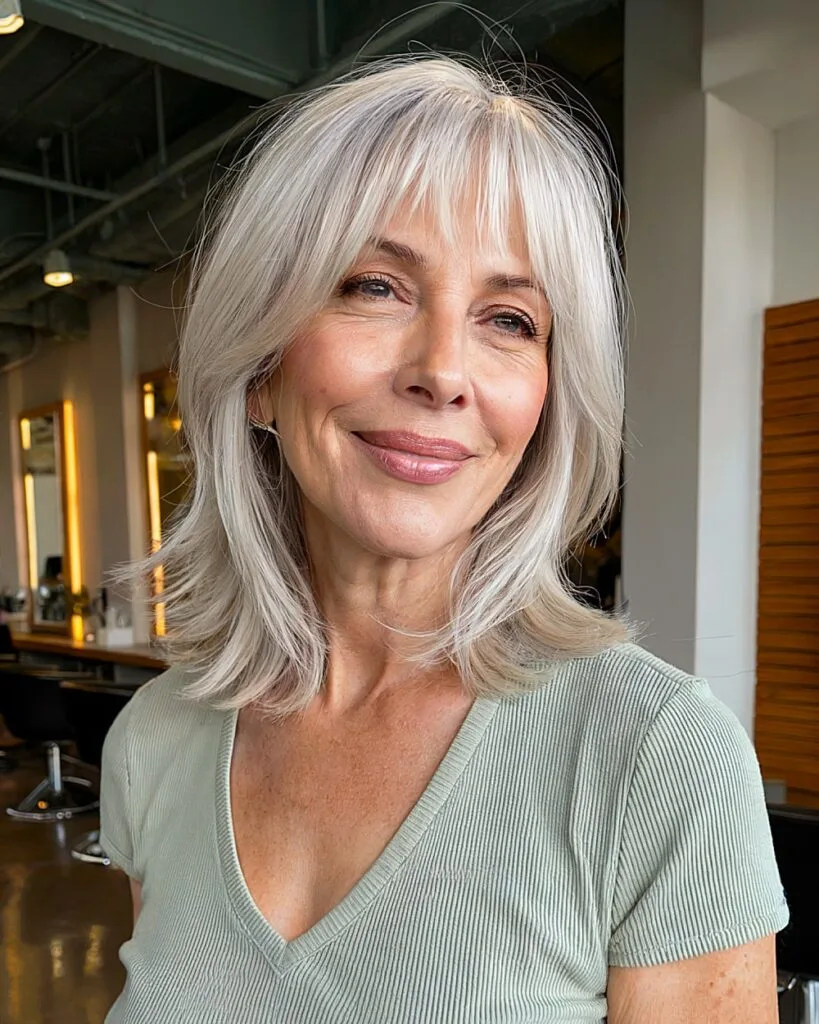 Layered gray haircut with wispy bangs and soft face-framing for women over 60