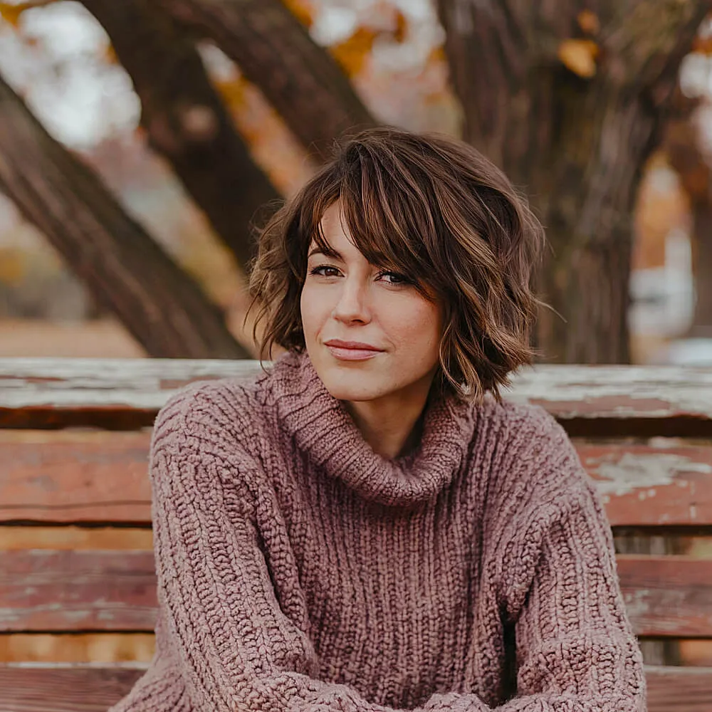 Layered shaggy bob for thick hair with side bangs and tousled waves