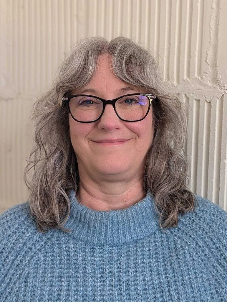 Shoulder-length wavy gray shag with glasses