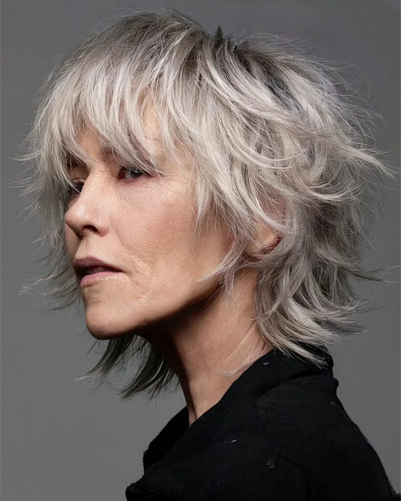 Edgy silver shaggy bob with razored layers and textured bangs for fine hair over 50